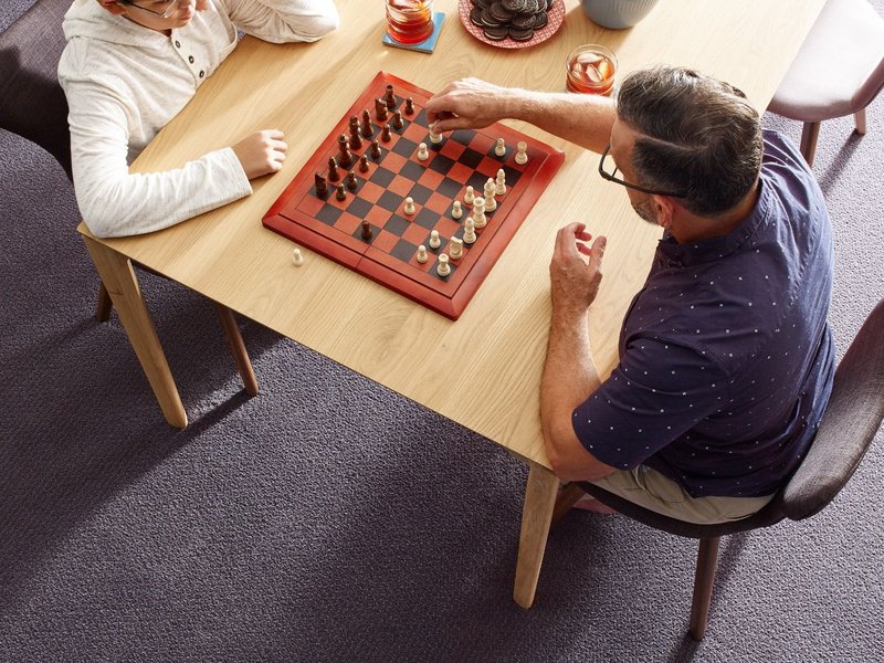 Here are some tips and tricks for preparing before your new floor arrives! | Family sitting across a table playing chess
